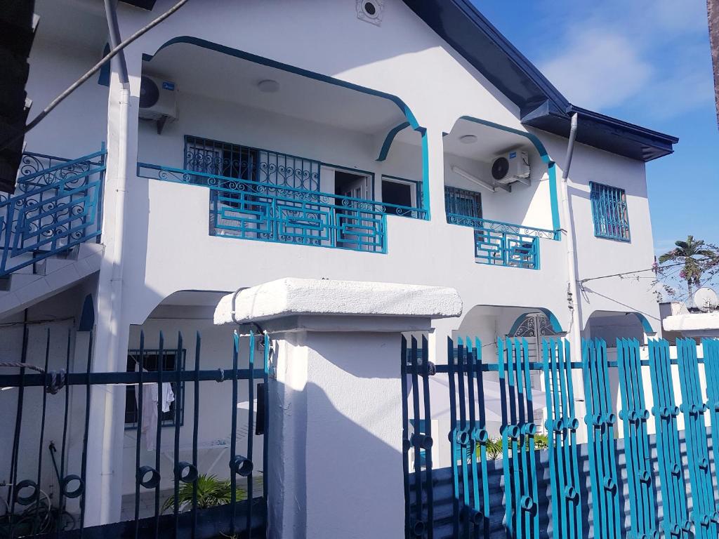 une maison blanche avec une clôture bleue dans l'établissement APPARTEMENT MAKEPE BM 2, à Douala