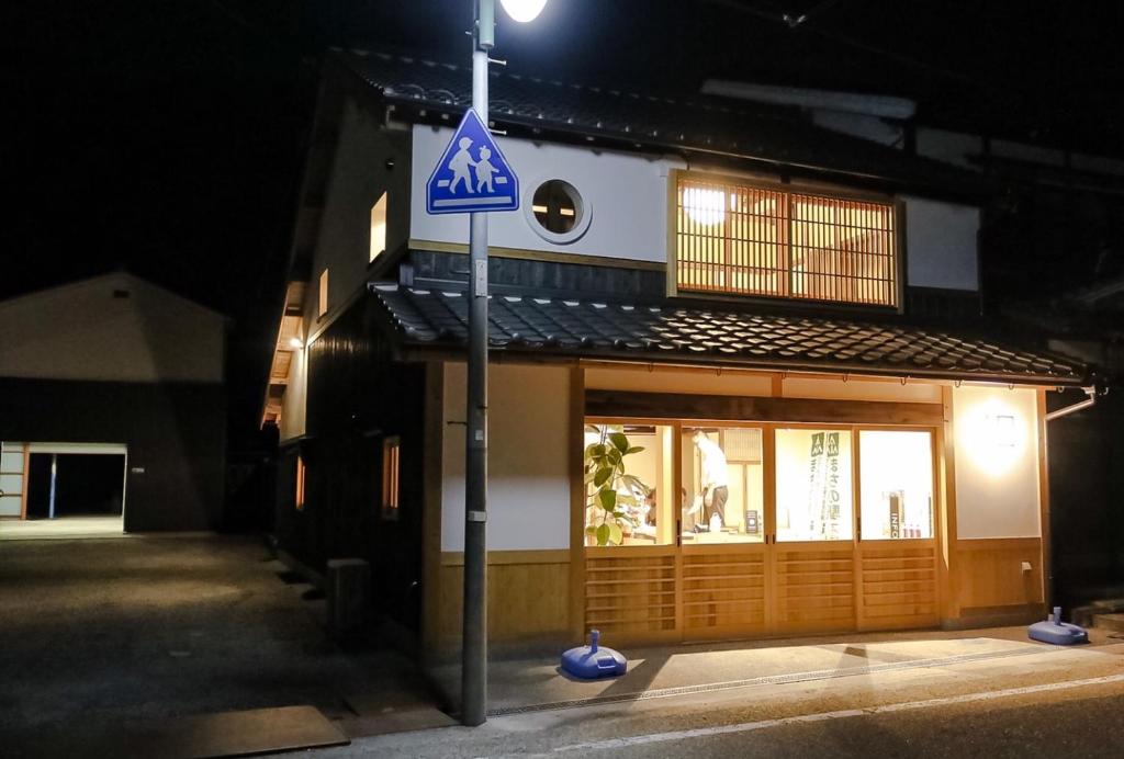 un letrero de la calle frente a un edificio por la noche en 北房まちの駅 ゲストハウス en Shimo-azae