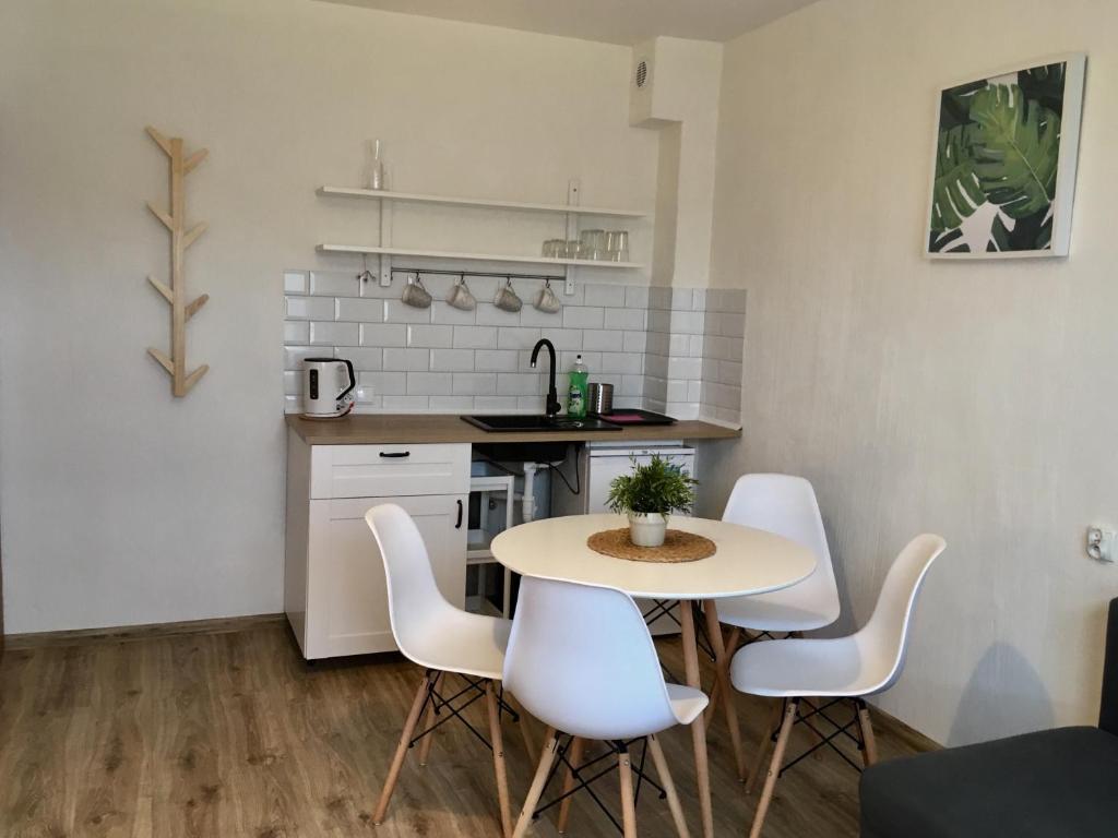 a small kitchen with a table and white chairs at Latarnik in Karwia