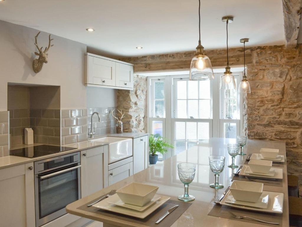 a kitchen with white cabinets and a table with wine glasses at no 8 main street in Sedbergh
