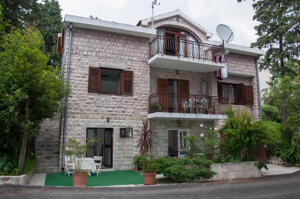 a large brick house with a balcony on a street at Vuksanovic Apartment in Herceg-Novi