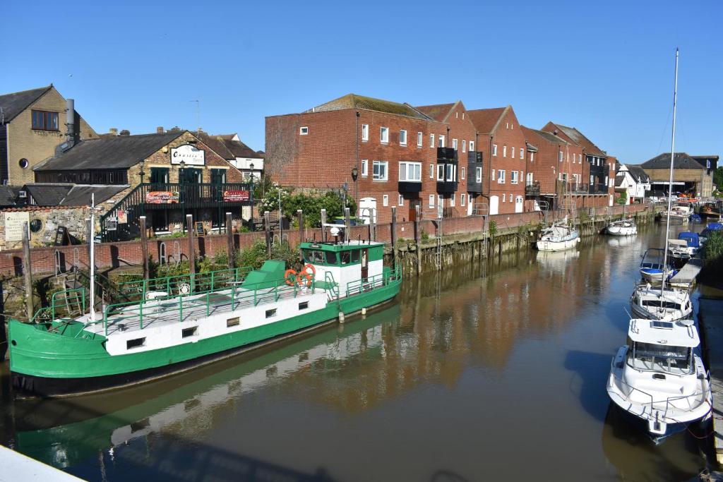 a green boat is docked in a canal with other boats at Boatyard View in Sandwich