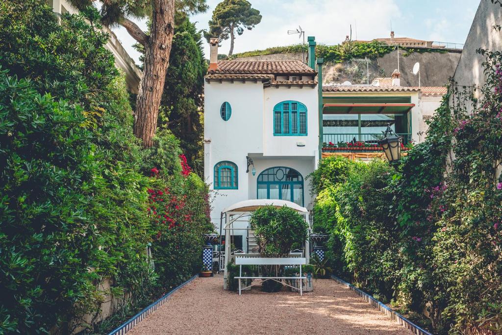 Uma casa branca com um banco à frente. em Casa Baulenas em Caldes d'Estrac