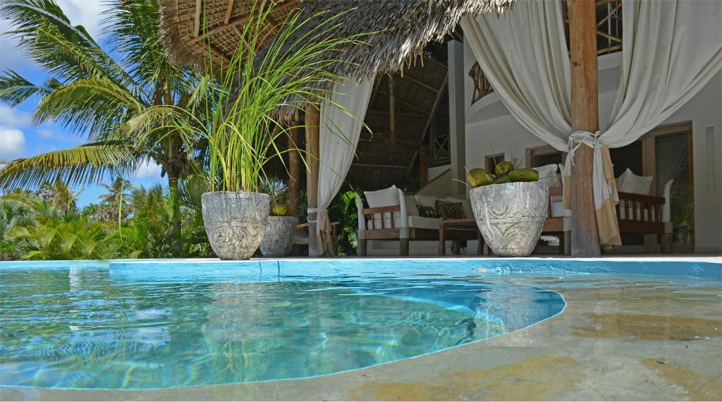a swimming pool with two plants in vases at The Lawford in Malindi