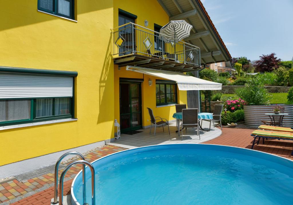 a swimming pool in front of a yellow house at Ferienwohnung Barth in Tittling