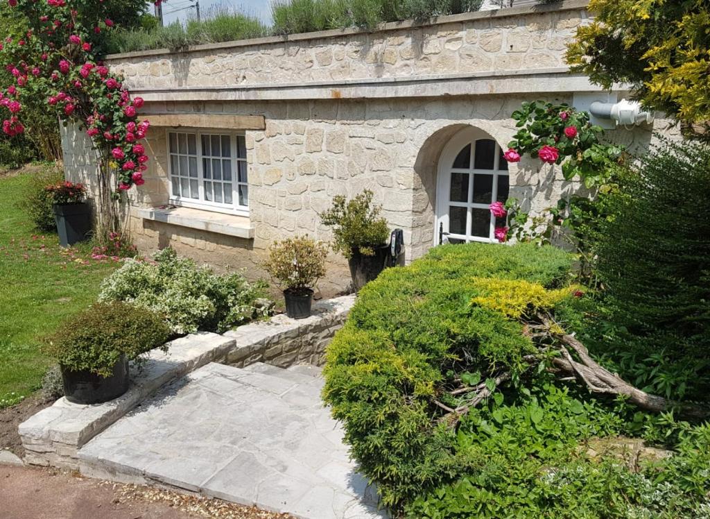 Champagne-sur-Oise的住宿－Sur la route des peintres，一座石头建筑,设有窗户和一些鲜花