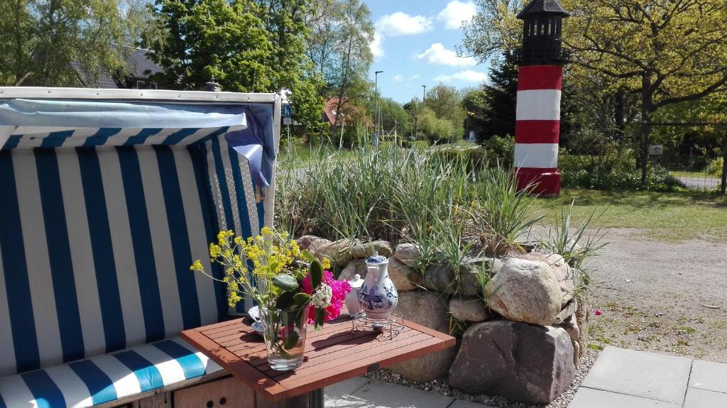 Una mesa con flores junto a un faro. en Ferienwohnanlage Sturmhöhe en Welt