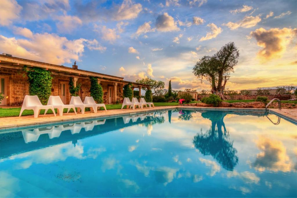 a swimming pool with chairs and a house at Masseria Sorani in Manduria
