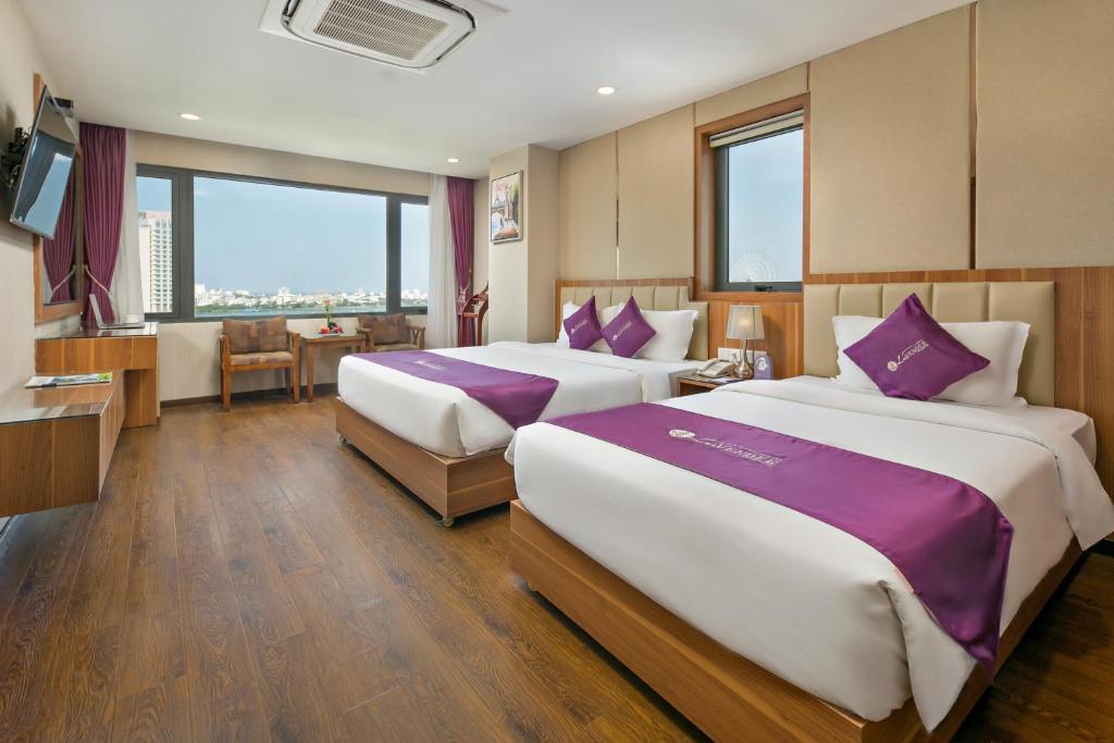 a hotel room with two beds with purple pillows at Lavender Riverside Hotel in Danang