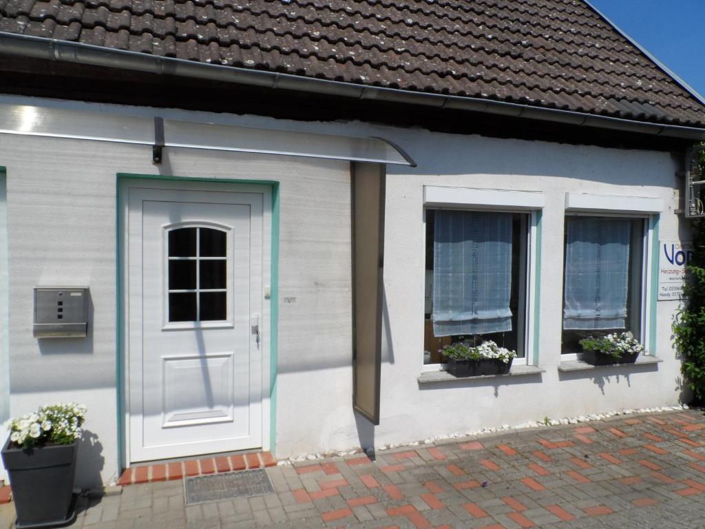 a white house with a door and two windows at Große rustikale Ferienwohnung am Stadtrand von Röbel an der Müritz mit Balkon in Röbel