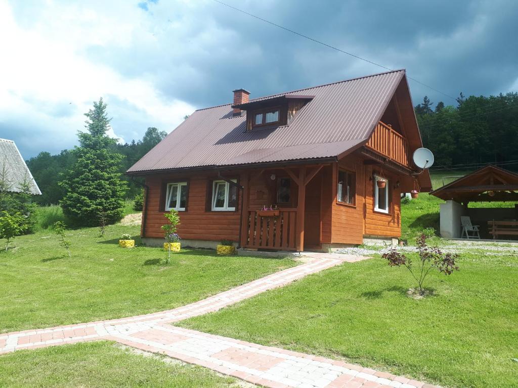 una casa de madera con techo de gambrel en Domek Gajowego en Ropienka