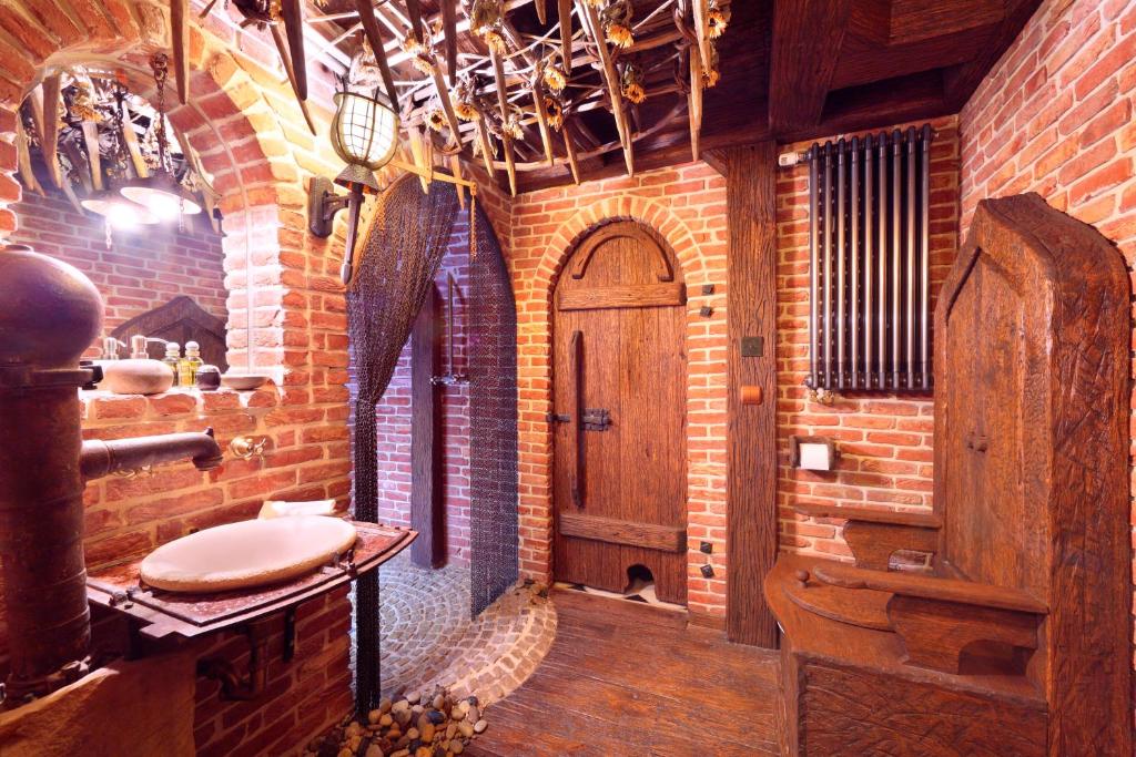 a brick bathroom with a sink and a wooden door at Attic Apartment Warszawa in Warsaw