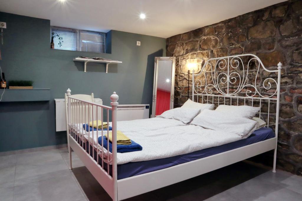 - un lit bébé blanc dans une chambre dotée d'un mur en pierre dans l'établissement Sofia Center Cave, à Sofia