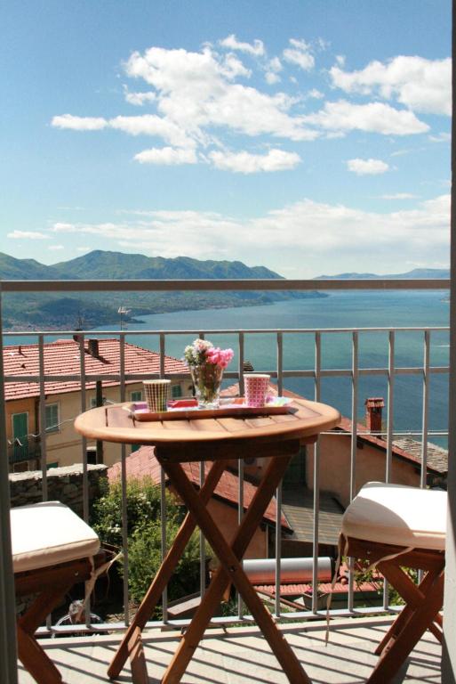 a table on a balcony with a view of the water at Vista Lago in Maccagno Superiore