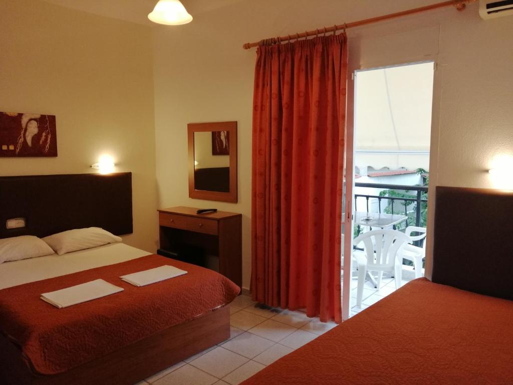 a bedroom with a bed and a window with a balcony at Giannis Hotel in Paralia Katerinis