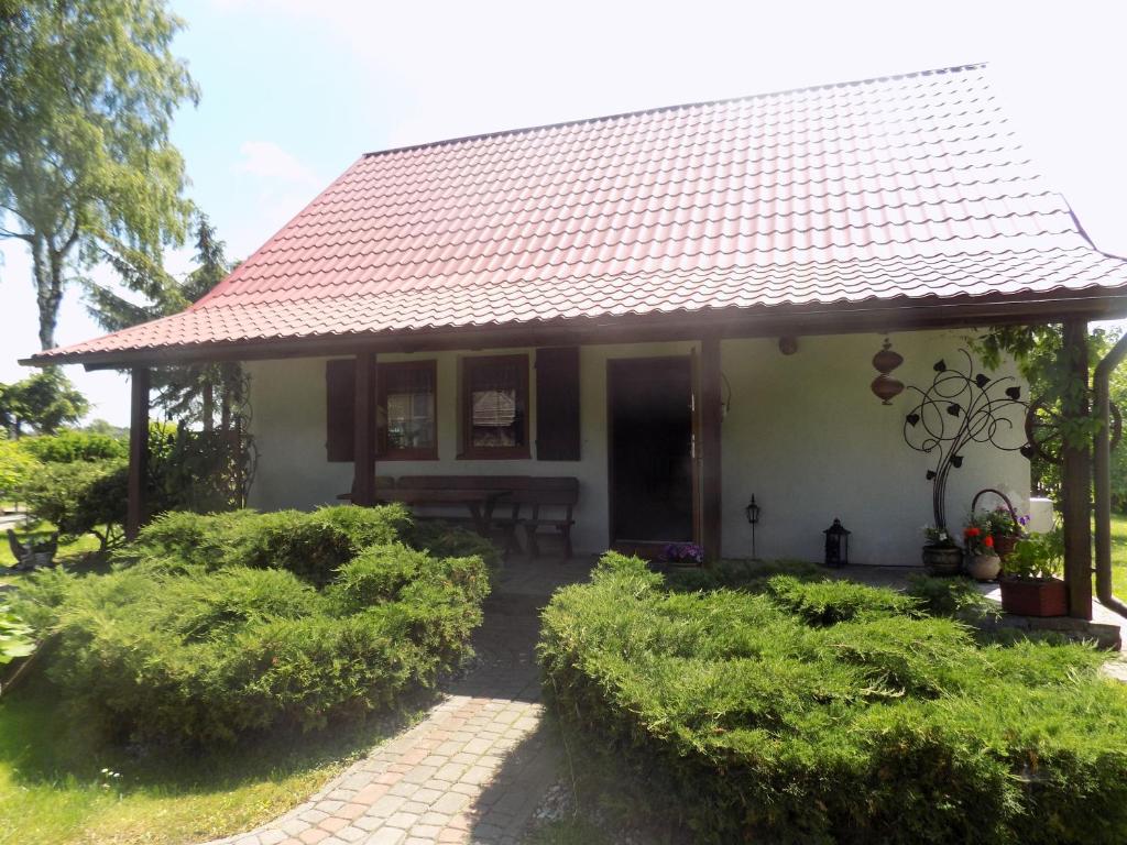 een klein wit huis met een rood dak bij Domek na suwalszczyźnie w Taciewie in Suwałki