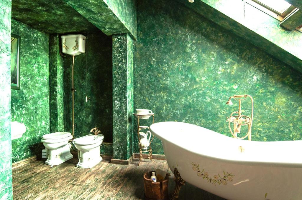 a green bathroom with two toilets and a tub at Attic Apartment Warszawa in Warsaw