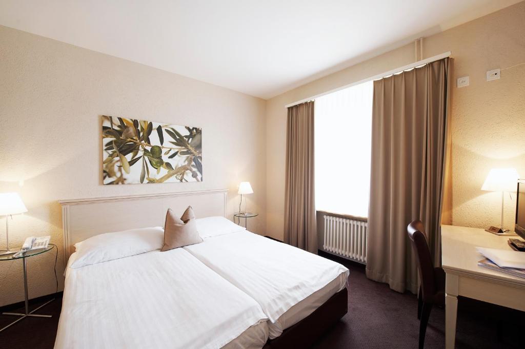 a hotel room with a white bed and a desk at Hotel Neufeld in Zürich