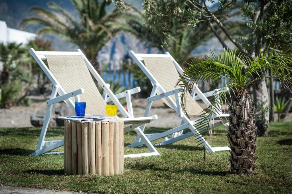 two white chairs sitting next to a palm tree at Mari del Sud Resort in Vulcano