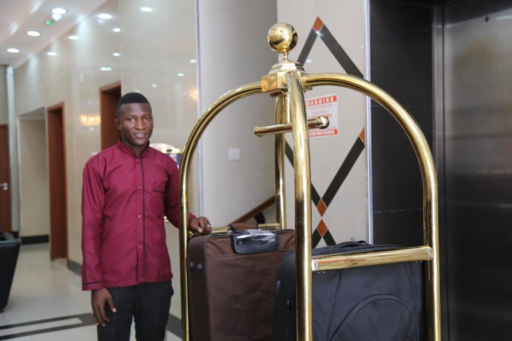 a man standing next to a gold luggage rack at Rainbow Hotel in Dar es Salaam