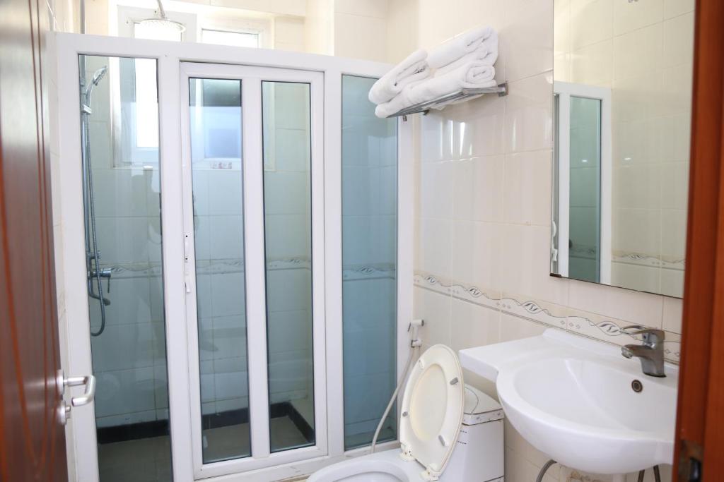 a bathroom with a shower and a toilet and a sink at Rainbow Hotel in Dar es Salaam
