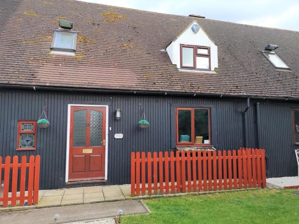 a black house with a red fence in front of it at Chalet Cottages in Streatley