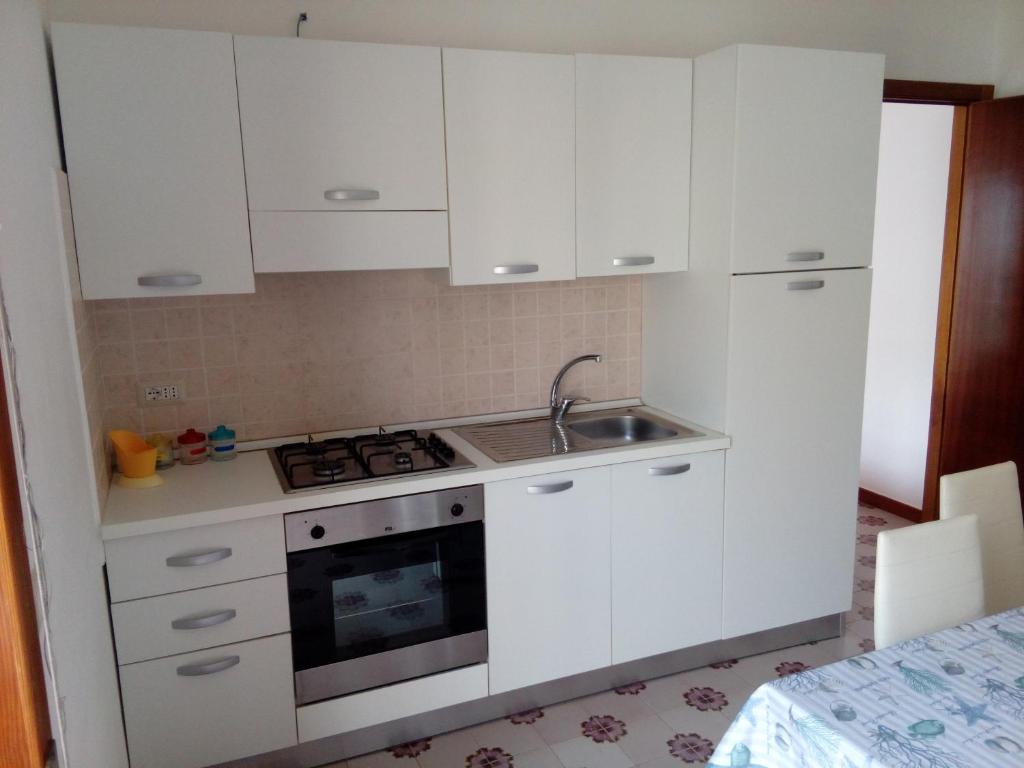 uma cozinha com armários brancos e um lavatório em A casa di Luca em Lido Conchiglia