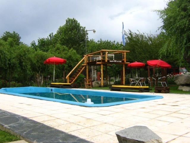 una piscina con tobogán y un parque infantil con sombrillas en Cabañas Tierra del Sol Aldea de Montaña en Los Árboles