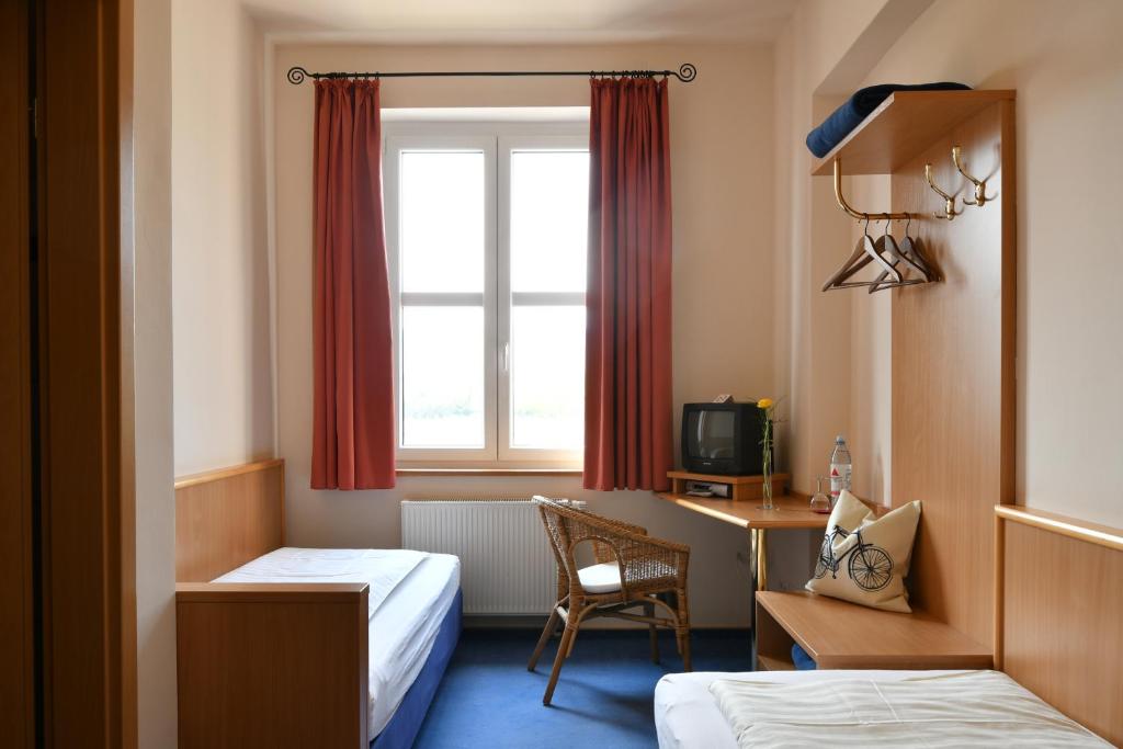 バート・デュルクハイムにあるGästehaus & Café Leezeのベッド2台、デスク、窓が備わるホテルルームです。