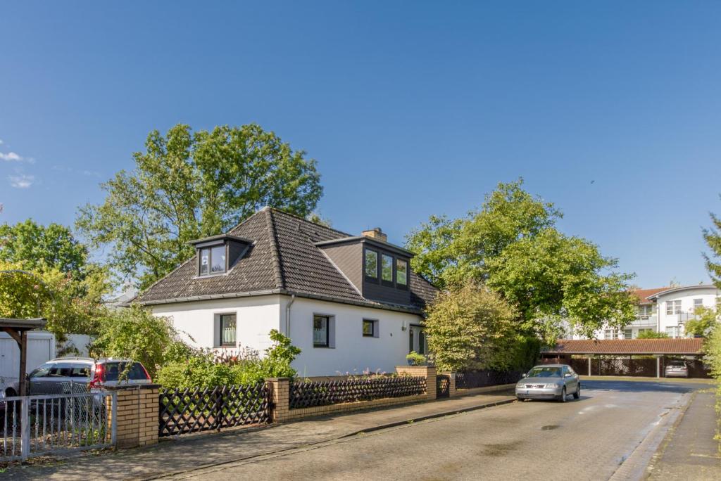 a white house with a black roof on a street at Private Room with own bathroom in Hannover