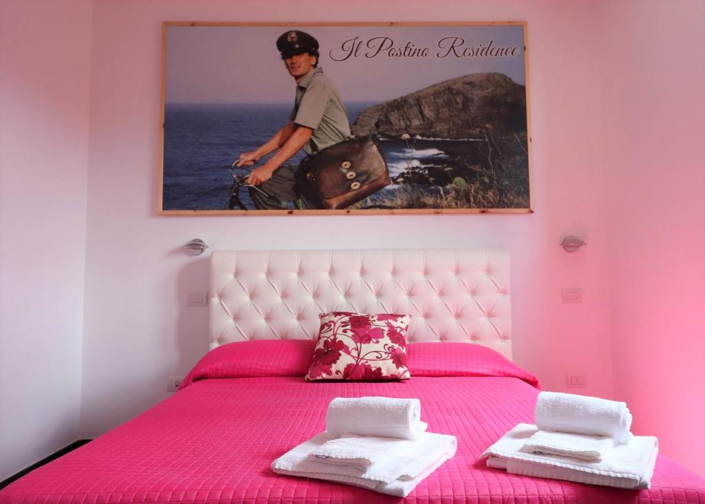 a pink bedroom with a pink bed with a picture on the wall at Casa Vacanze Il Postino in SantʼAgata sui Due Golfi