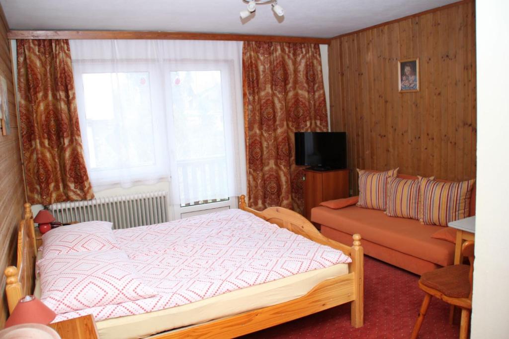 ein Schlafzimmer mit einem Bett, einem Sofa und einem Fenster in der Unterkunft Gasthof Edelweiss in Semmering