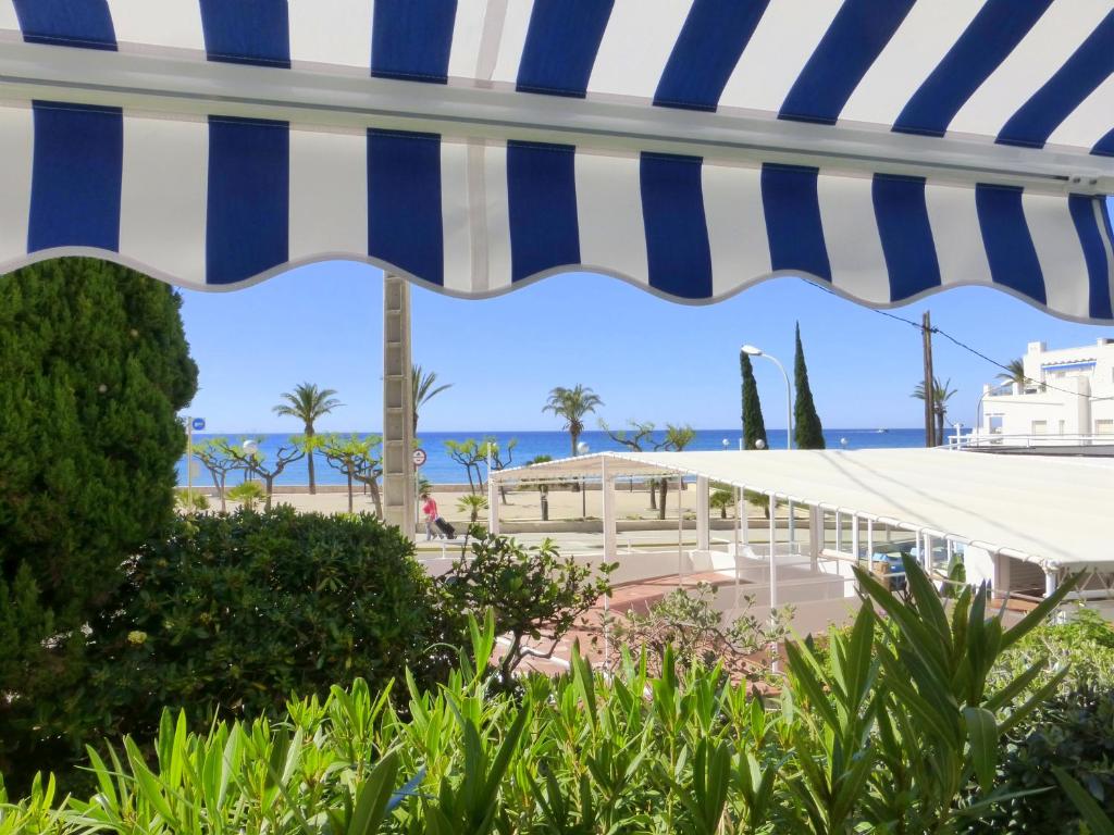 einen Blick auf den Strand unter einem blauen und weißen Sonnenschirm in der Unterkunft Rentalmar El Capitan in Vandellòs i l’Hospitalet de l’Infant