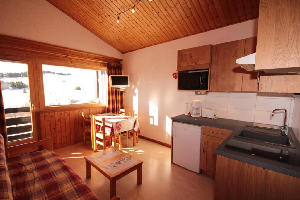 uma cozinha com um lavatório e uma mesa num quarto em Appt 4/5 pers. Les Saisies front de neige em Les Saisies