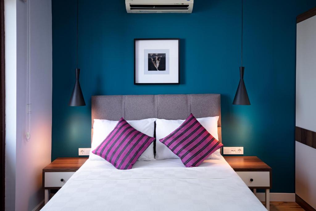 a blue bedroom with a bed with two purple pillows at Mono Hotel in Antalya