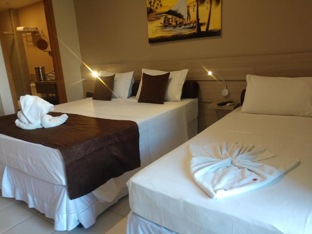 2 Betten in einem Hotelzimmer mit Handtüchern darauf in der Unterkunft MARULHOS RESORT - STÚDIOS TEMPORADA in Porto De Galinhas