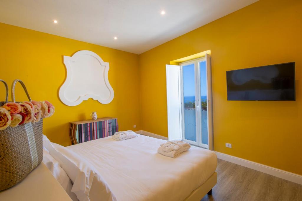 1 dormitorio con paredes amarillas, 1 cama y ventana en Appartamento Suite Melina, en Praiano