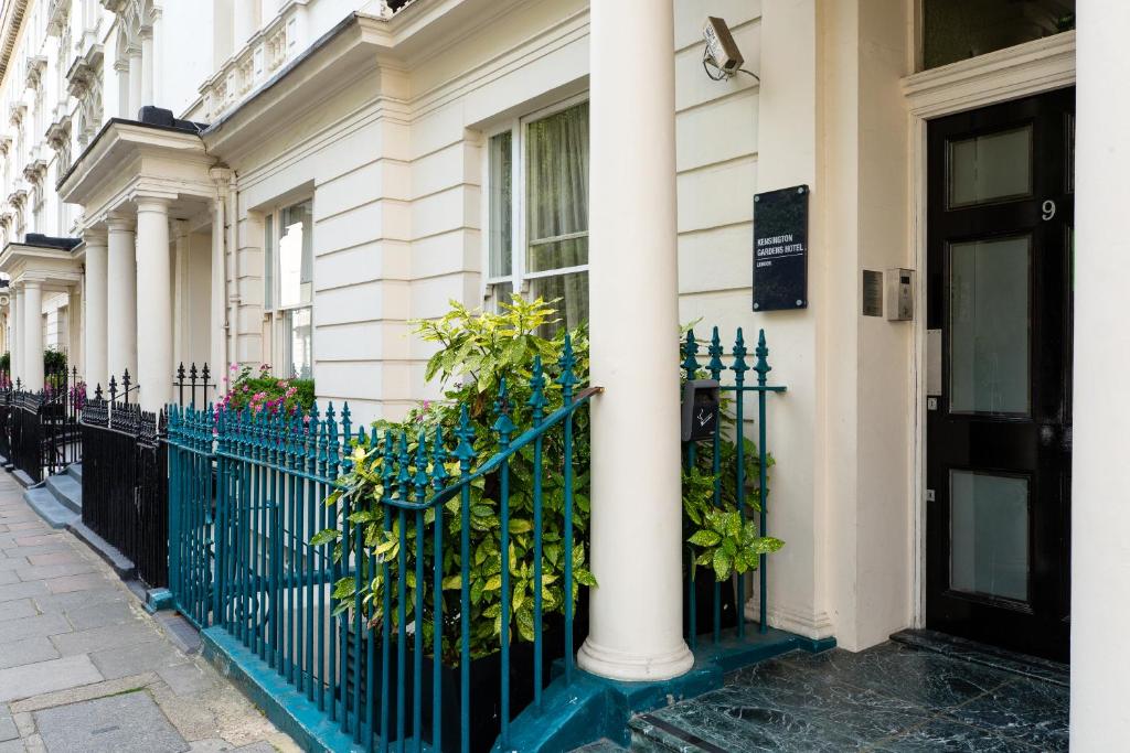 Una cerca frente a una casa con flores. en Kensington Gardens Hotel, en Londres