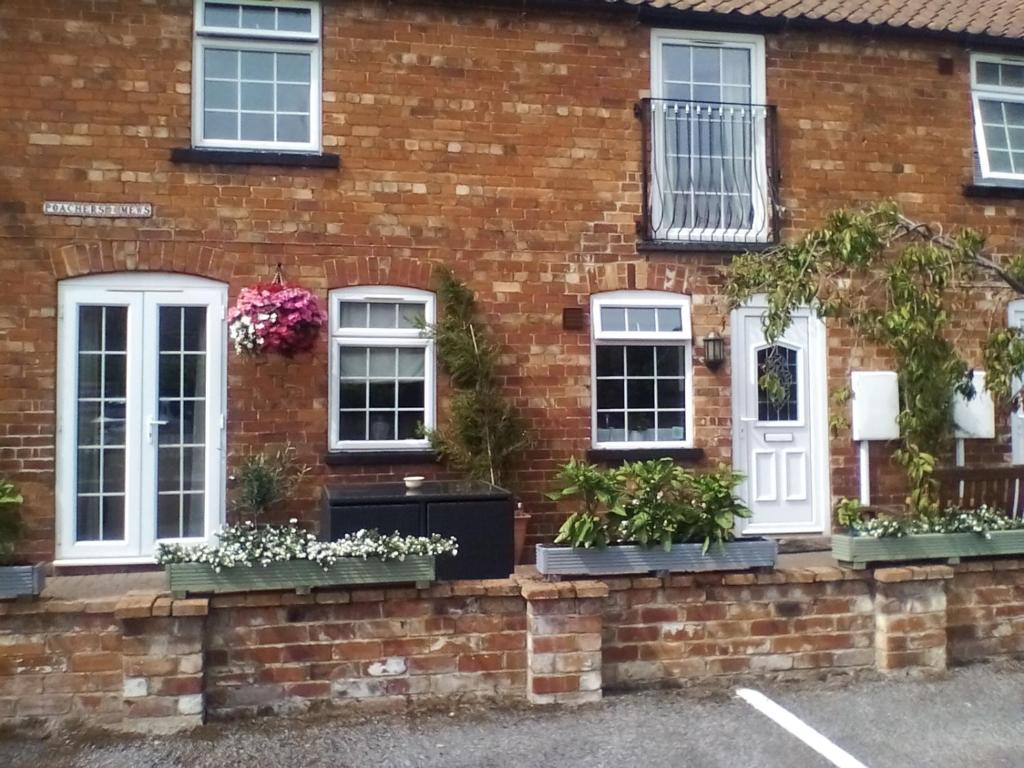uma casa de tijolos com janelas brancas e vasos de plantas em The Lincolnshire Poacher Inn em Metheringham