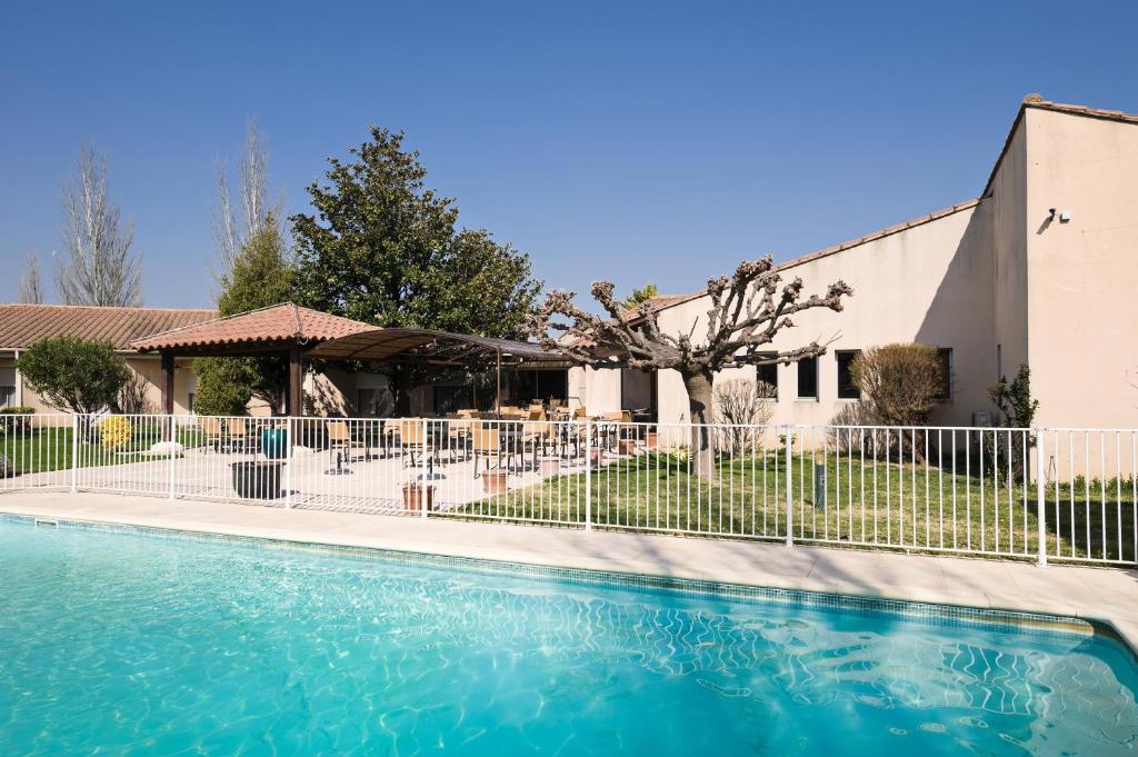 a swimming pool in front of a building at Hôtel Paradou Avignon Sud in Avignon