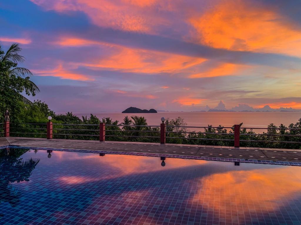 a pool with a view of the ocean at sunset at Golden Hill Resort in Wok Tum