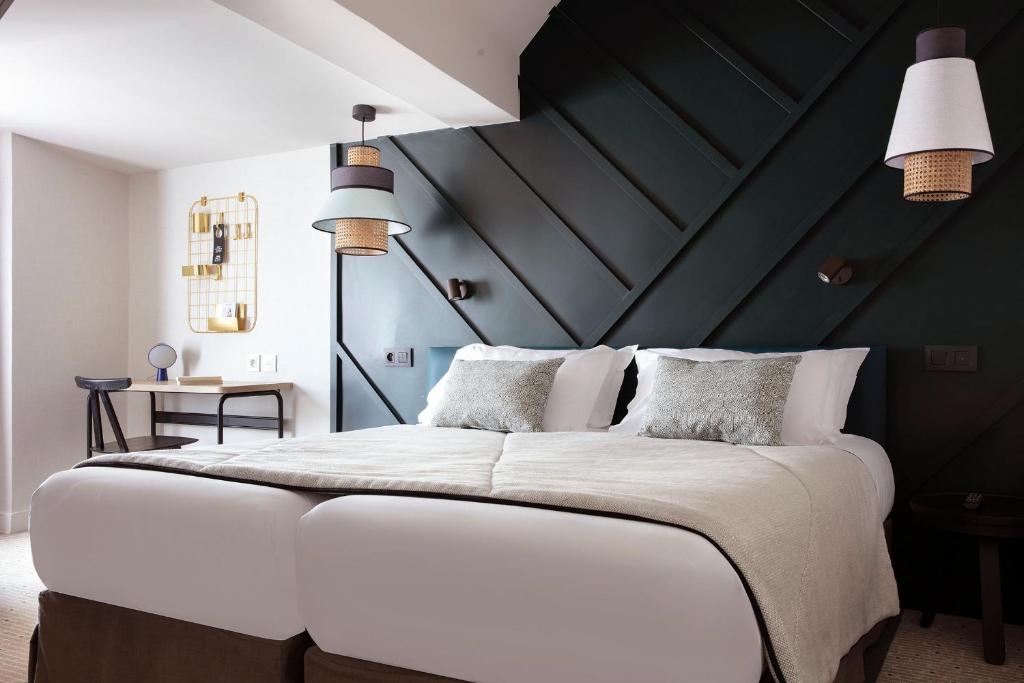 1 dormitorio con 1 cama blanca grande y pared negra en Hotel Bastille Speria, en París