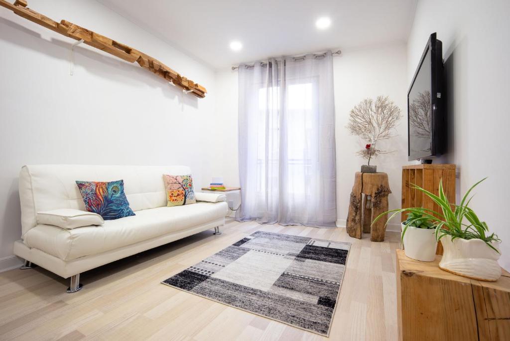 uma sala de estar com um sofá branco e uma televisão em Sustraia - Local Rentss em San Sebastián