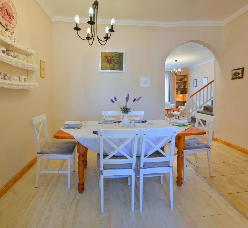 a dining room with a white table and chairs at Lux Apartman Villa in Hajdúszoboszló