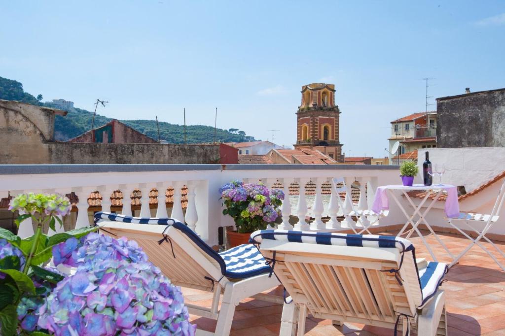 a balcony with chairs and a table and flowers at Sorrento Marida Rooms in Sorrento