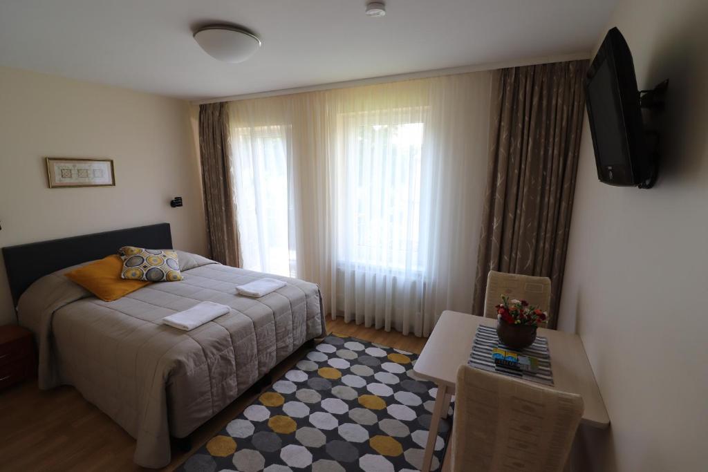 sypialnia z łóżkiem, stołem i telewizorem w obiekcie Nileja w Wilnie