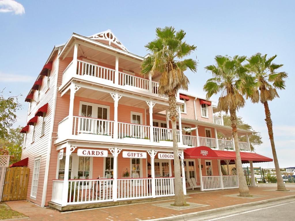 un edificio rosa con palmeras delante en The Riverview Hotel - New Smyrna Beach en New Smyrna Beach