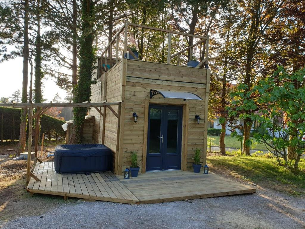 une petite maison avec une porte bleue sur une terrasse en bois dans l'établissement Le domaine des hauts de canche Magnifique Tiny house avec Spa, à Étaples