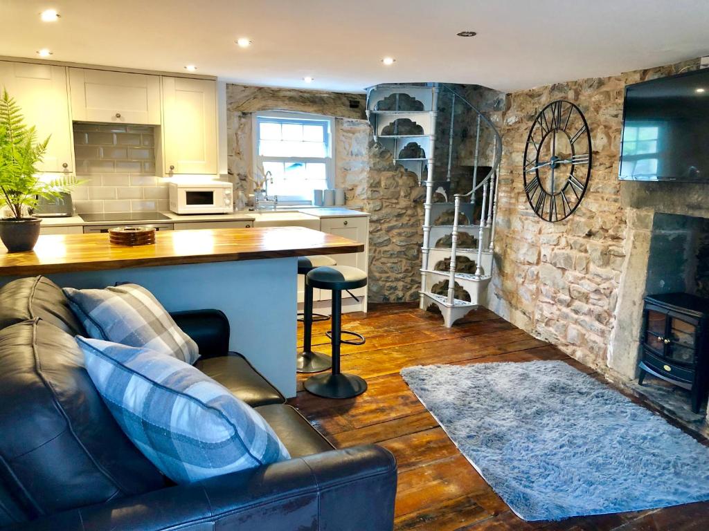 a living room with a leather couch and a kitchen at secret cottage in Sedbergh