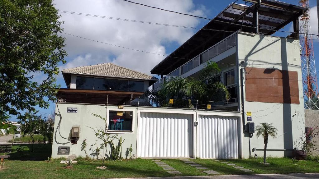 a white house with a gate in front of it at Airport Pousada in Cabo Frio